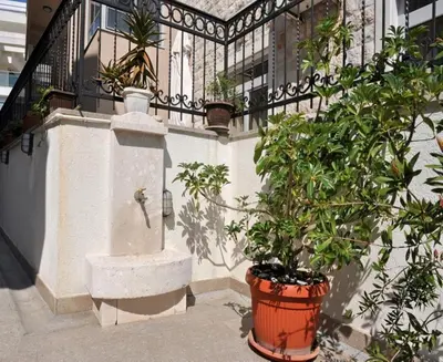 a building with a balcony with plants and a fence at Apartments Franićević in Petrovac na Moru