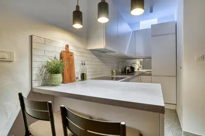 a kitchen with white cabinets and a counter with chairs at Museum Palazzo Suite by MN Property in Kotor