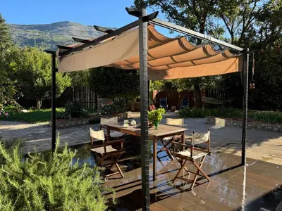 a wooden table and chairs under an umbrella at Charming Cozy Home on the Beach in Kaluđerac