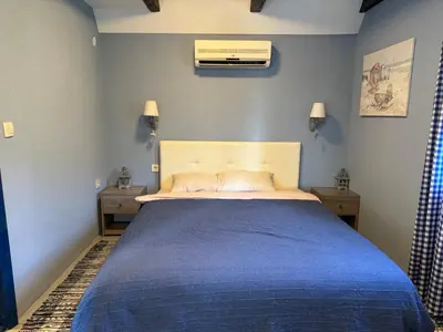 a bedroom with a large bed with a blue blanket at Charming Cozy Home on the Beach in Kaluđerac