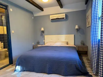 a bedroom with a large bed with a blue bedspread at Charming Cozy Home on the Beach in Kaluđerac