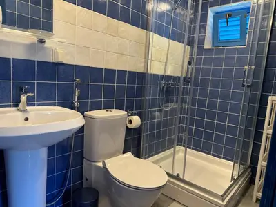 a blue tiled bathroom with a toilet and a sink at Charming Cozy Home on the Beach in Kaluđerac