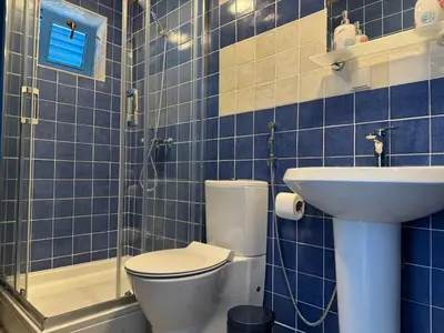 a blue tiled bathroom with a toilet and a sink at Charming Cozy Home on the Beach in Kaluđerac