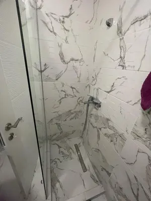 a bathroom with a shower with white marble walls at Studio 78 - Tuški put in Podgorica