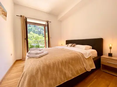a bedroom with a large bed and a window at Fiumera Kotor Apartment in Kotor