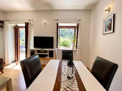 a dining room with a table and chairs and a television at Fiumera Kotor Apartment in Kotor