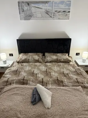 a bedroom with a large bed with two tables at Hill Apartment in Podgorica