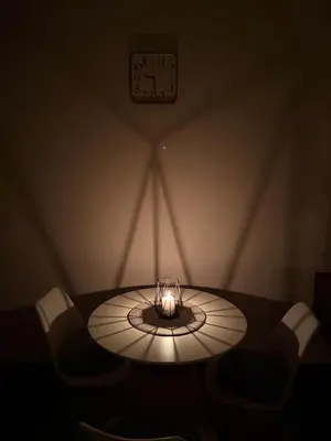 a table in a room with a clock on the wall at Hill Apartment in Podgorica