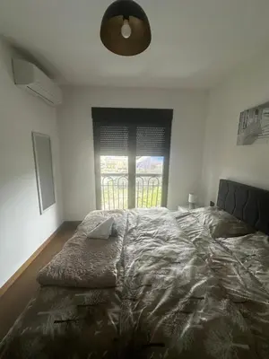 a bedroom with a large bed with a large window at Hill Apartment in Podgorica