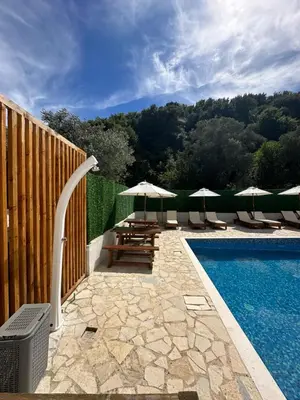 a pool with chairs and umbrellas next to a fence at Eman Villas in Ulcinj