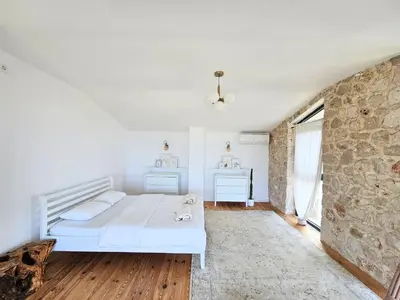 a bedroom with a white bed and a stone wall at Stone Villa at the Vrelo in Dobra Voda