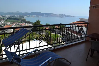 a balcony with a blue chair and a view of the water at Apartments Milosevic in Bar