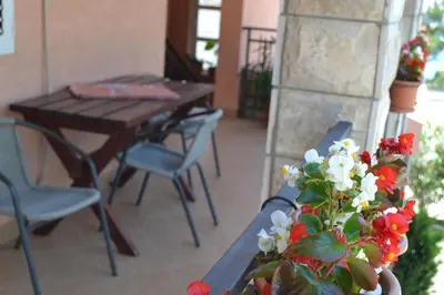 a porch with a table and chairs and a vase of flowers at Apartments Milosevic in Bar