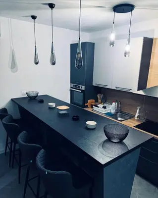 a kitchen with a black counter with bar chairs at Vila AS Krimovica in Krimovice