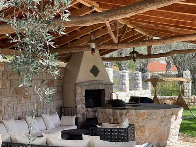an outdoor patio with a stone fireplace and a wooden ceiling at Apartments Villa St. Bar in Bar