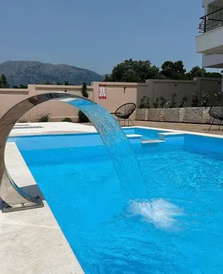 a blue swimming pool with a water fountain at Apartment Complex with Pool in Bar, Montenegro in Bar