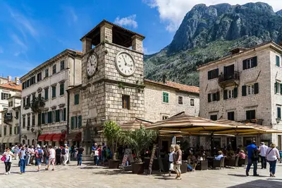 a building with a clock tower with a mountain in the background at Artintime Apartments in Kotor