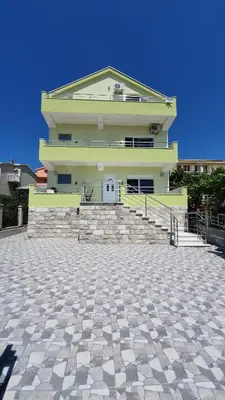 a large building with stairs and a building with a blue sky at Meli Apartman in Krimovice