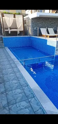 a large swimming pool with blue tiles on the ground at Meli Apartman in Krimovice