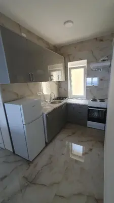 a kitchen with white appliances and a marble floor at Meli Apartman in Krimovice