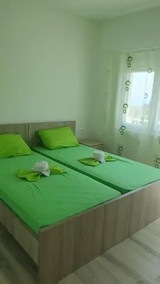 a bedroom with two beds with green sheets and a window at Meli Apartman in Krimovice