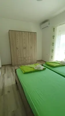 two beds in a room with green sheets at Meli Apartman in Krimovice