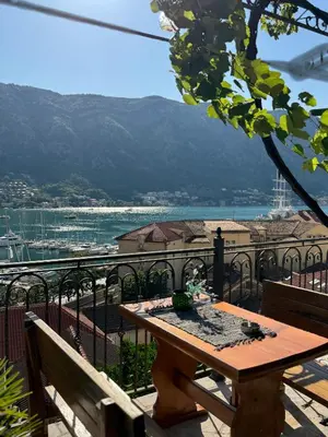 a wooden table on a balcony with a view of the water at Old Town Gem - Rooftop Terrace with Bay View in Kotor