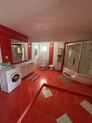 a bathroom with a red tile floor and a washing machine at Marija 2 Apartman in Ulcinj