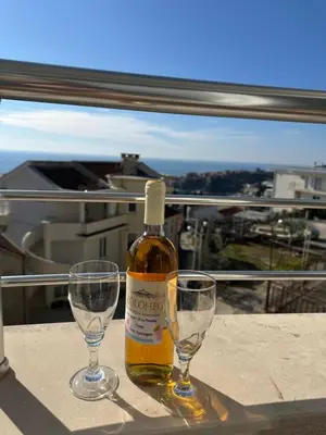 a bottle and two wine glasses sitting on a table at Marija 2 Apartman in Ulcinj