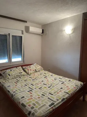 a bedroom with a bed with a comforter and two windows at Marija 2 Apartman in Ulcinj
