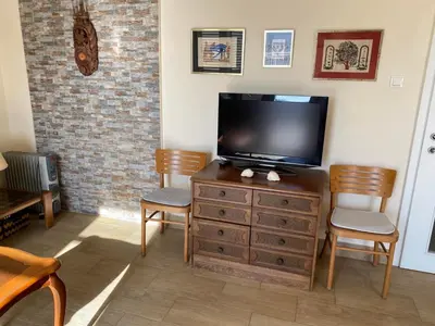 a living room with a tv on a dresser with chairs at Vila Dube in Ulcinj
