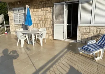 a patio with a table and chairs and an umbrella at Vila Dube in Ulcinj
