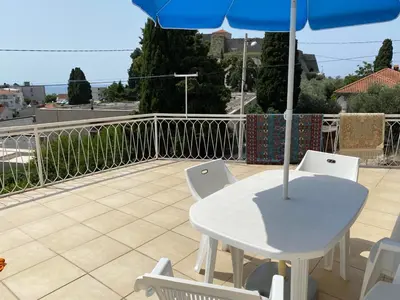 a white table and chairs with an umbrella on a balcony at Vila Dube in Ulcinj