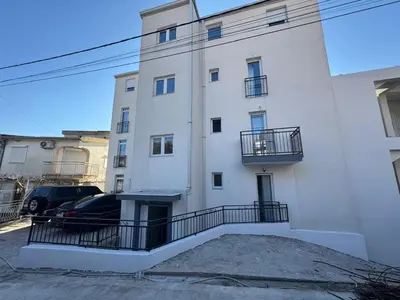 a white building with a car parked in front of it at Apartment Alex in Dobra Voda
