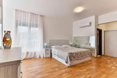 a bedroom with two beds and a large window at Lux Apartment KORDA in Rafailovici