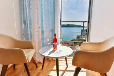 a table with two chairs and a bottle of wine at Lux Apartment KORDA in Rafailovici