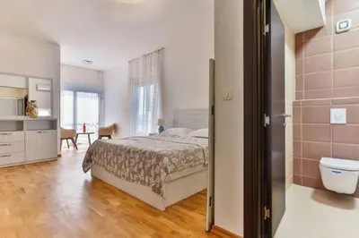 a bedroom with a bed and a bathroom with a toilet at Lux Apartment KORDA in Rafailovici