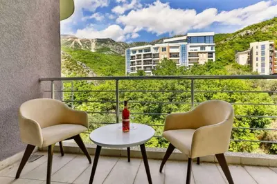 a balcony with two chairs and a table with a bottle of wine at Lux Apartment KORDA in Rafailovici