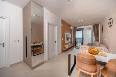 a kitchen and living room with a table and chairs at Wave Apartments - Dobra Voda in Bar
