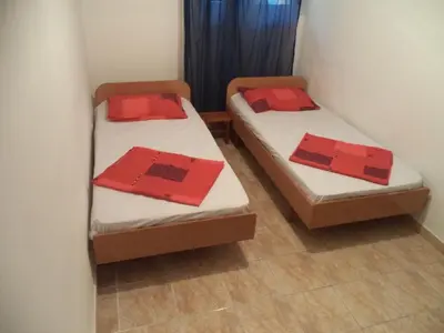 two beds in a room with red pillows on them at Vito Apartments Sutomore in Sutomore