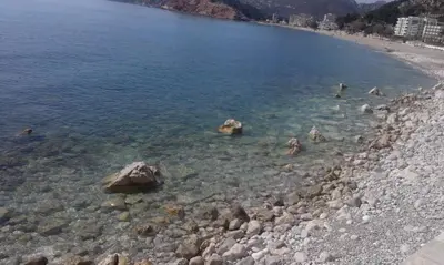 a large body of water with rocks and a beach at Apartments Markovic Sutomore in Sutomore