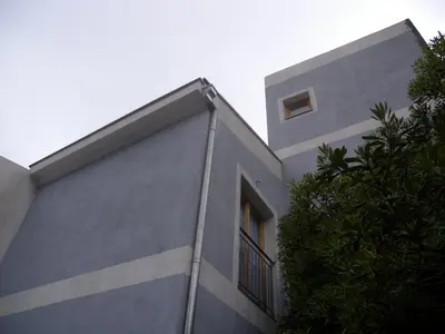 a gray building with a window and a tree at Apartments Markovic Sutomore in Sutomore