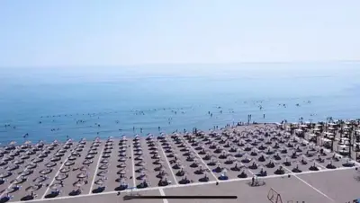 a beach with umbrellas and people in the water at Apartment D&A in Ulcinj