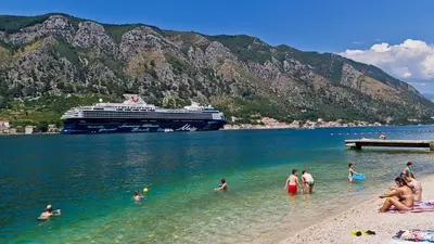 a group of people in the water at a beach with a cruise ship at BMB Apartments Kotor in Kotor