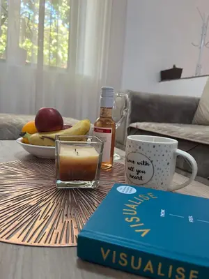 a table with a book and a cup of coffee and a plate of fruit at Apartment Stari Konak in Virpazar