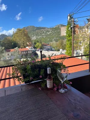 a bottle of wine and a glass on a table with flowers at Apartment Stari Konak in Virpazar