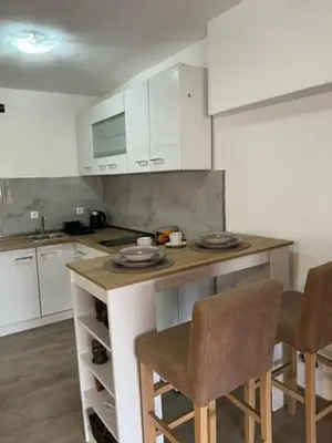 a kitchen with white cabinets and a counter with chairs at Apartment Stari Konak in Virpazar
