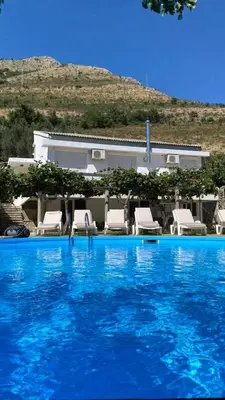 a large blue swimming pool with chairs and a house at Villa Rezevici in Katun