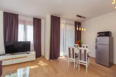 a living room with a television and a table with chairs at Opium Mar Apartments in Petrovac na Moru