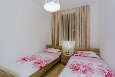 two twin beds in a room with pink flowers at Opium Mar Apartments in Petrovac na Moru